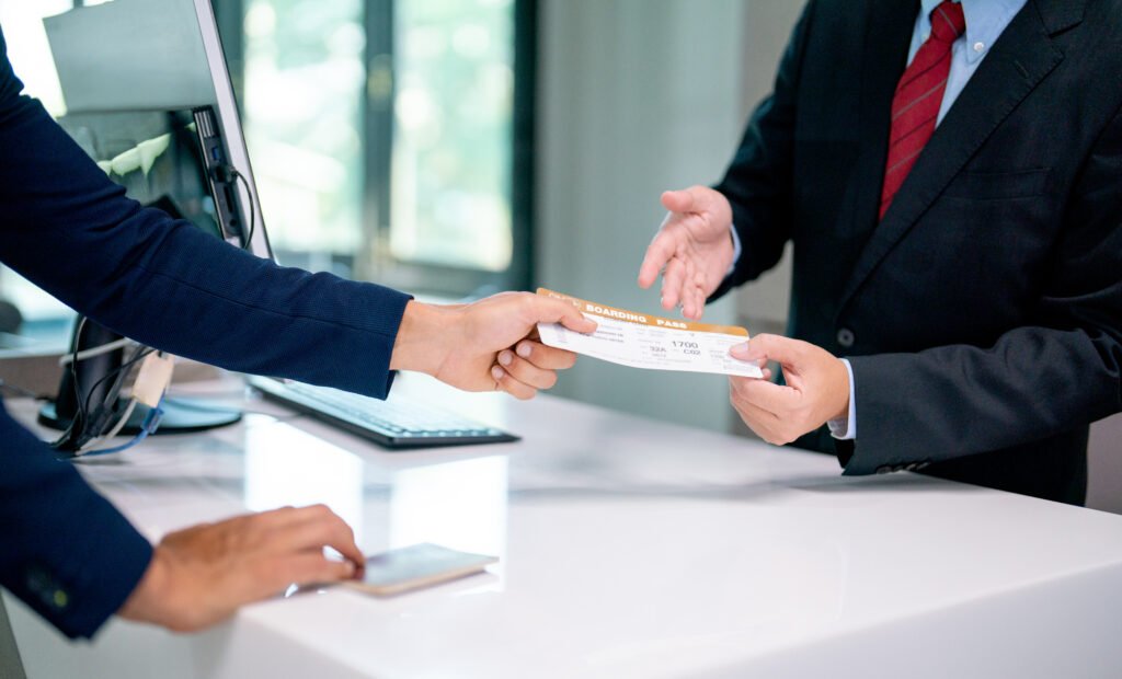 Close up hands of airline staff give boarding pass for flight to the customer at service counter