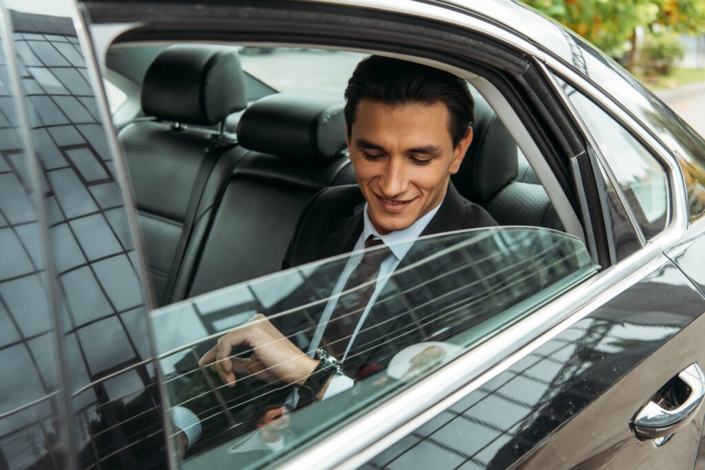 Smiling businessman looking at wristwatch in taxi